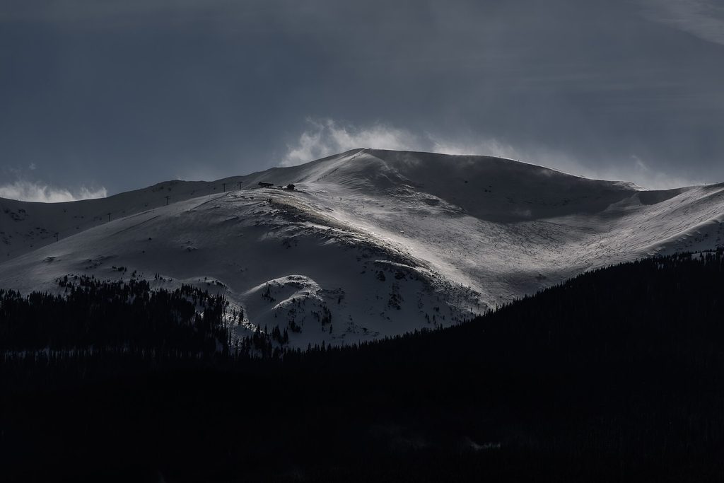 A snow-covered ski slope and mountain under a moody winter sky